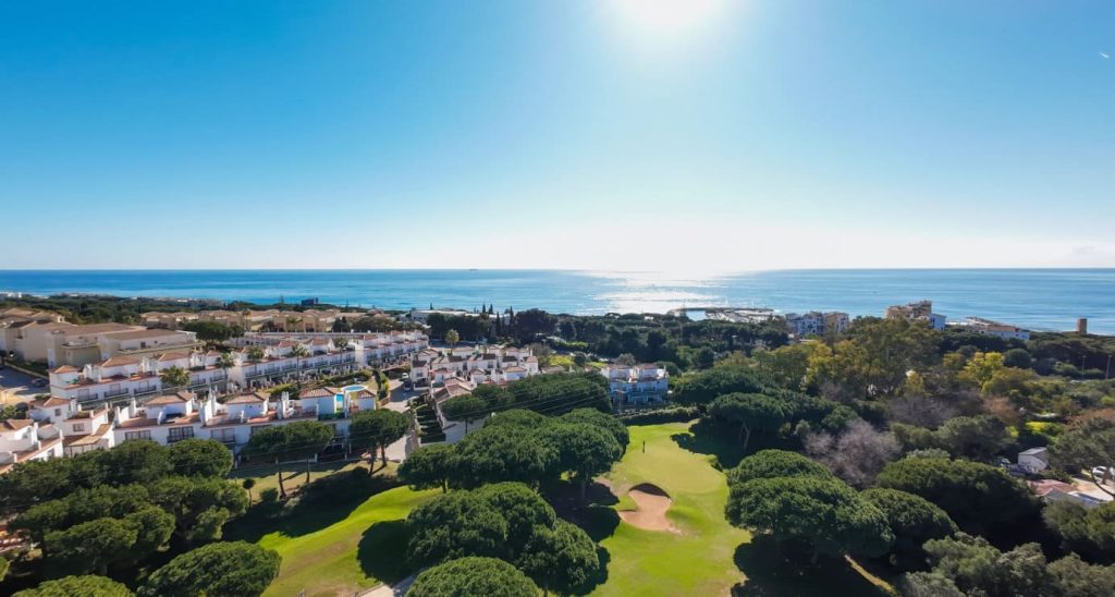 vista aérea de un campo de golf en la costa del sol con el mar de fondo